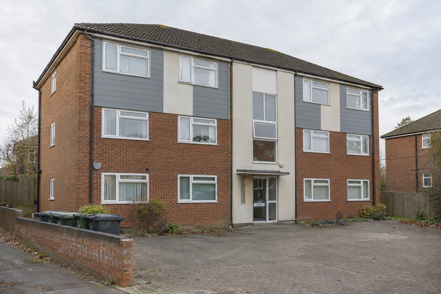 Three-storey flats with brickwork and upper-floor cladding in England, illustrating lower-rise cladding funding.